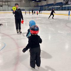 Skating instructor with 2 small kids on ice